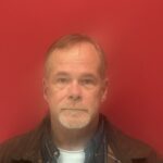 Man in front of a red background.